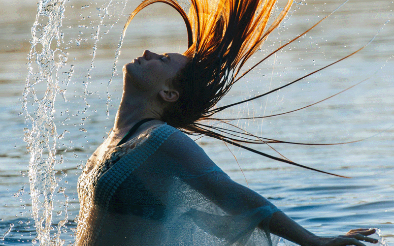 Experiences-3 Side view of young woman in water throwing wet hair back arms open